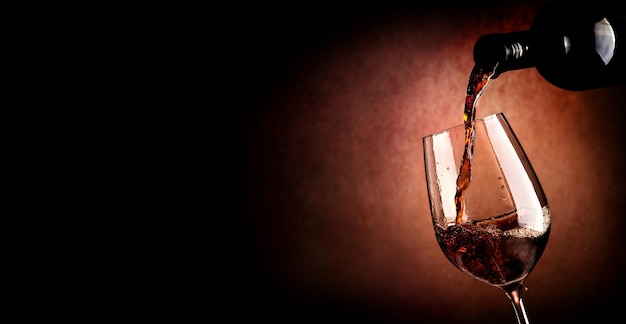 Wine pouring in wineglass on the brown background