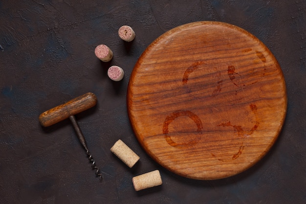 Wine stains on round wooden board, corks and corkscrew. 