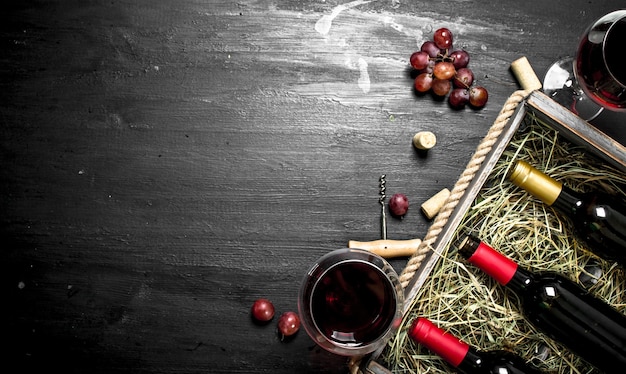 Wine table. Red wine in an old box with a corkscrew. On the black chalkboard.