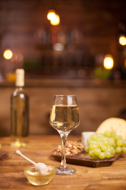 Wine tasting in a vintage pub with fresh grapes on a wooden table. Bowl of tasty honey.