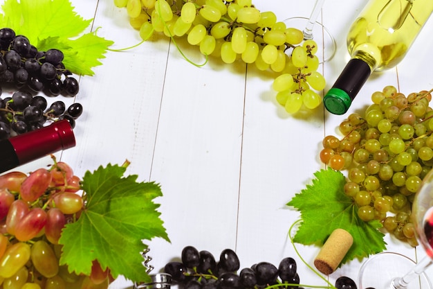 Wine with branches of white grapes. On a wooden table.