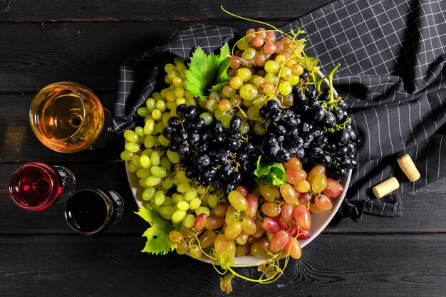 Wine with branches of white grapes. On a wooden table.