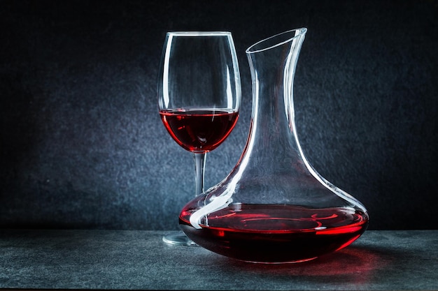 Wineglass and decanator with red wine on dark background