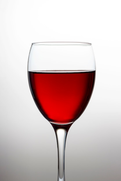 Wineglass with red wine close-up isolated on light gradient 