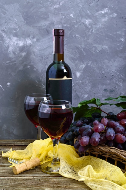 Wineglasses with red wine, bottle, and fresh grapes