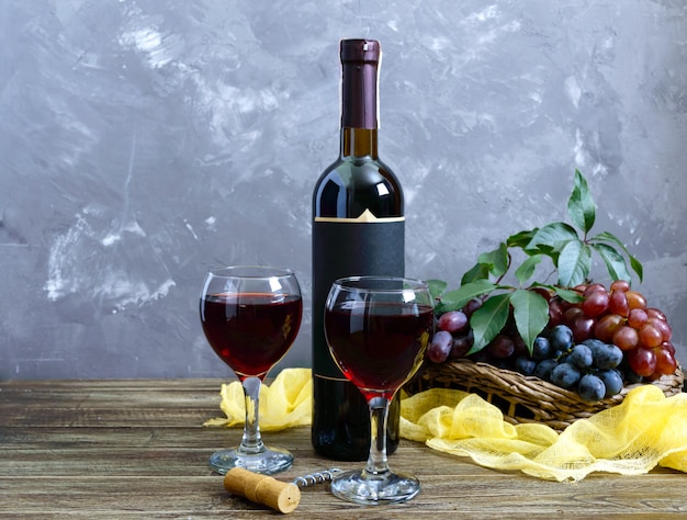 Wineglasses with red wine, bottle, and fresh grapes