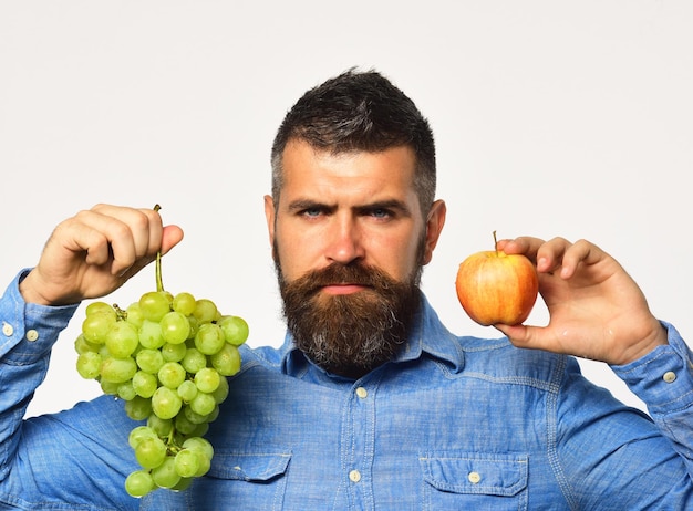 Winegrower with serious face holds grapes and red fruit