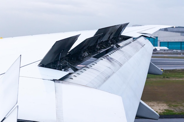 The wing of an aircraft with open flaps on the wing that is landing