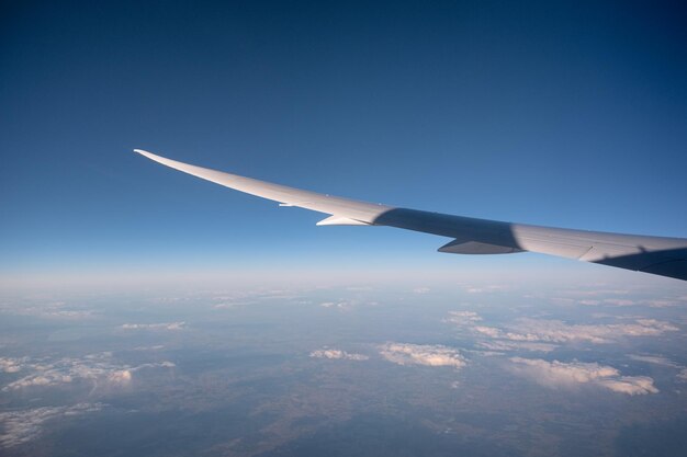 Wing of airplane flying above in blue sky on sunny day