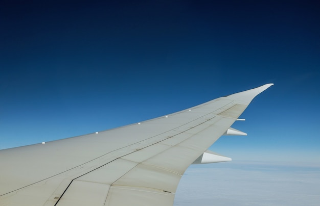 Wing of an airplane flying above the clouds of an aircraft