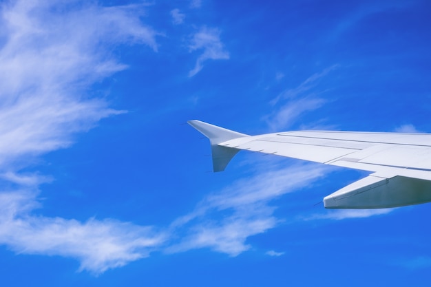 Wing of airplane flying above the clouds in the sky