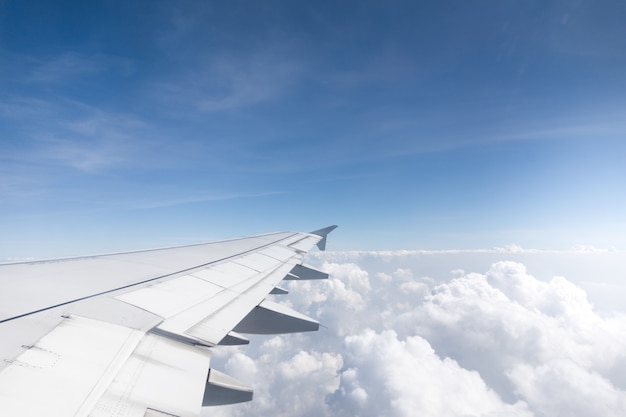 Wing of an airplane flying above the morning clouds