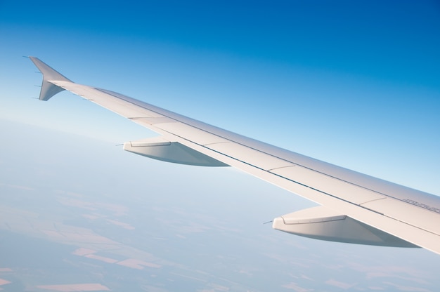 The wing of an airplane in the sky above the clouds