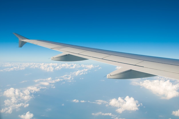 The wing of an airplane in the sky above the clouds