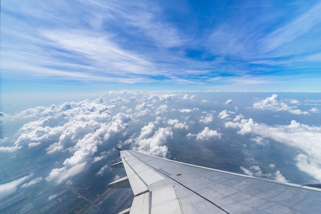 写真 ウインドウを通して青空の背景に雲の上を飛んで飛行機の翼。