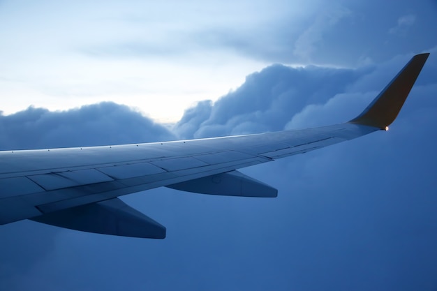 夕方の雲の上を飛行中の翼旅客機