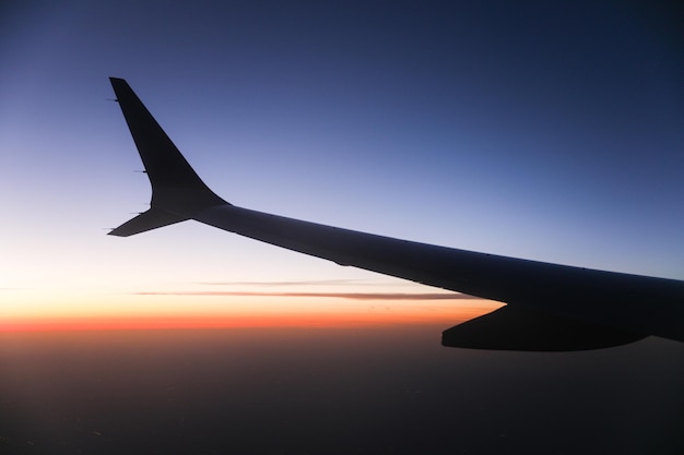 A wing of a plane is seen from the window of a plane.