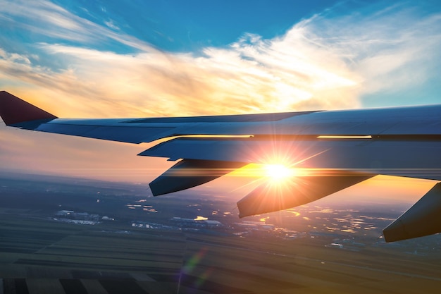 Wing of the plane on sunset sky background Flying and traveling view from airplane window on the wing on sunset time Looking over aircraft wing in flight Airplane taking off at sunset