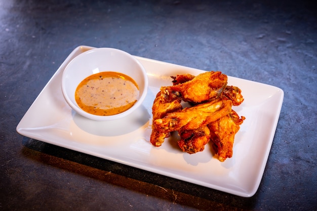 Wings with barbecue sauce on a black background, on a white plate