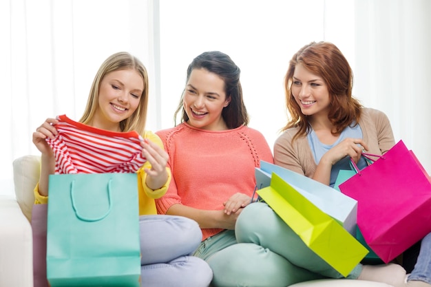 winkel- en lifestyleconcept - drie lachende tienermeisjes met veel boodschappentassen thuis