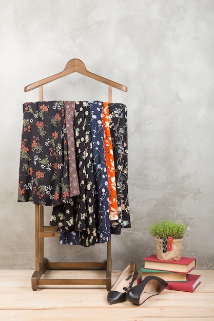 Winkel- en stijlconcept kledingrek met trendy jurken in schoenen met bloemenprint en boeken