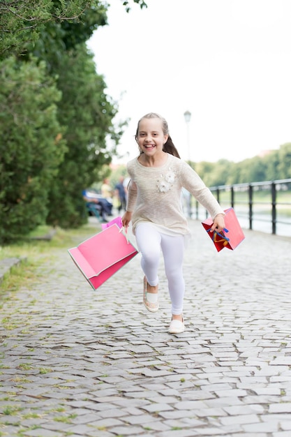 Winkelconcept Mooi klein meisje dat op straat loopt met de roze boodschappentassen