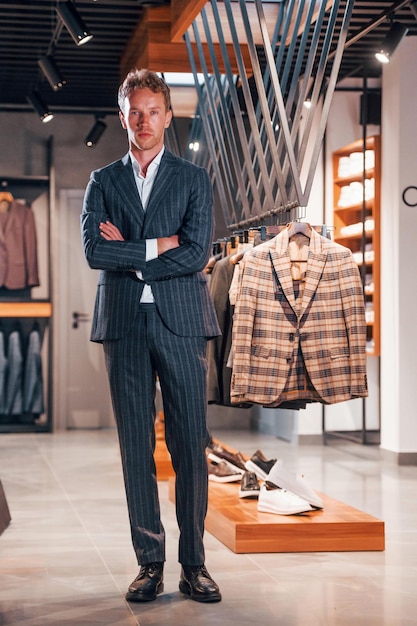 Winkeldag Jonge kerel in moderne winkel met nieuwe kleren Elegante dure kleding voor mannen