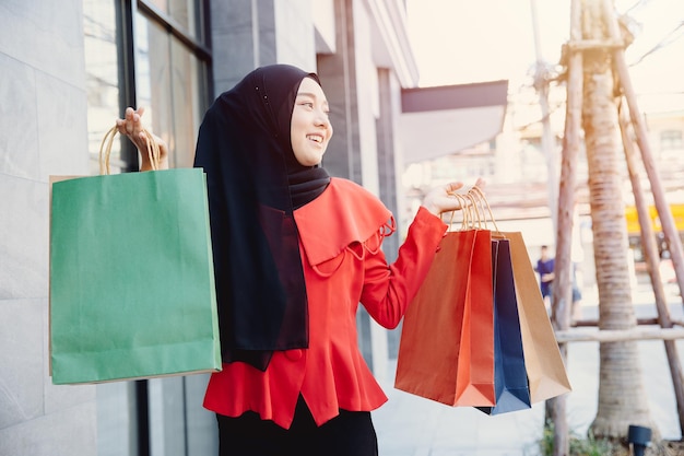 Winkelen Arabische moslim volwassen vrouw in sluier hijab kleding met tassen lopen in de stad straat genieten van een gelukkige glimlach.