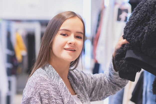 Winkelen Een jong meisje kiest kleding in een winkel
