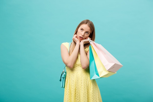 Winkelen en verkoop Concept: mooie ongelukkige jonge vrouw in gele elegante jurk met boodschappentas.