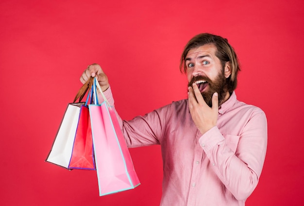 Winkelen geluk gelukkige bebaarde man met huidige pack vrolijke brutale hipster houd cadeau papieren boodschappentas verjaardag verrassing op feest man met pakket voorbereiden op vakantie beste verkoopaanbieding