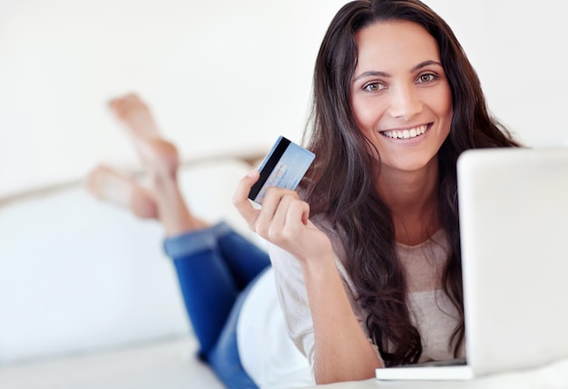 Winkelen is slechts een klik verwijderd Portret van een jonge vrouw die een creditcard vasthoudt terwijl ze een laptop gebruikt