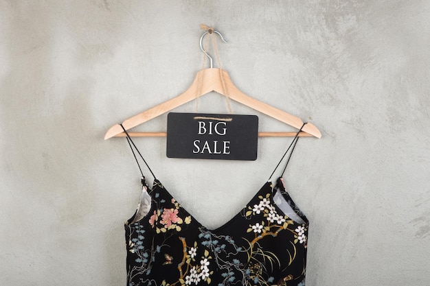 Winkelen korting concept schoolbord met tekst Big Sale en jurk in bloemmotief op een hanger