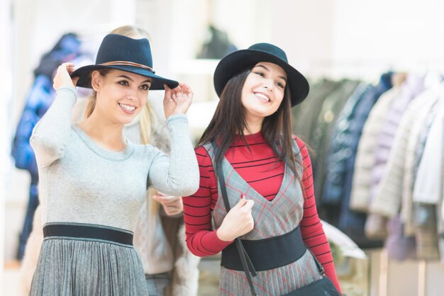 Winkelen Mooie vrolijke meisjes in een boetiek Kleding hoeden passen