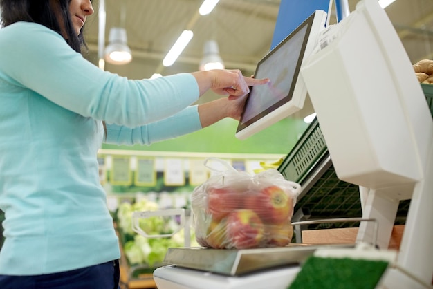 winkelen, verkopen, consumentisme en mensenconcept - vrouw die appels op de schaal weegt in een supermarkt