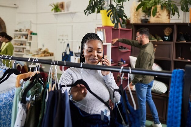 Winkelende vrouw en telefoontje voor modepraat in een winkel met uitverkoop of korting Zwarte persoon of tevreden klant op een smartphone voor productkeuzepromotie of communicatie in een boetiek