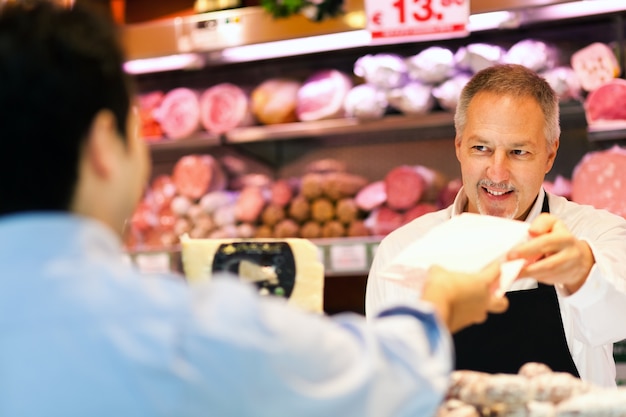 Winkelier die een klant in een kruidenierswinkel dient