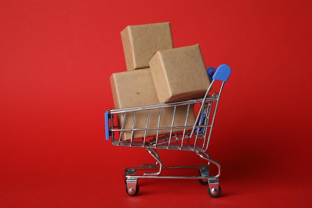 Winkelkarretje met dozen op rode achtergrond Logistiek en groothandelconcept