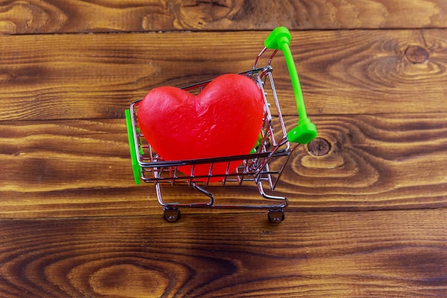 Winkelwagen met groot rood hart op houten achtergrond Valentijnsdag concept