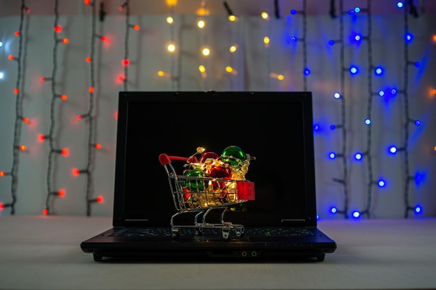 Winkelwagentje met kerstballen en slingers op het toetsenbord van de laptop