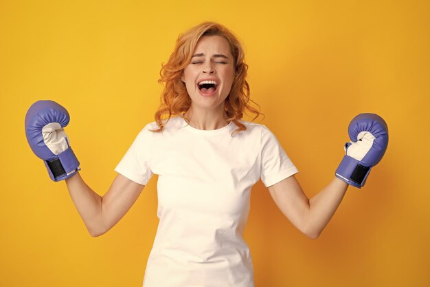 Winnaar vrouwelijke bokser met haar handen omhoog opgewonden Geïsoleerd op gele achtergrond Opgewonden vrouw