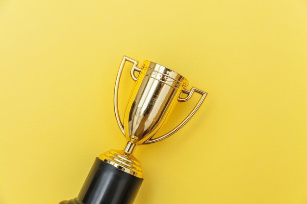 Winner or champion gold trophy cup isolated on yellow colorful background