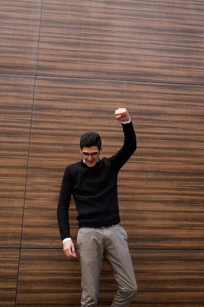 winner champion victory success. business man celebrating career breakthrough or important deal. hand in the air punch gesture. wood texture wall background. outdoors street. free space concept