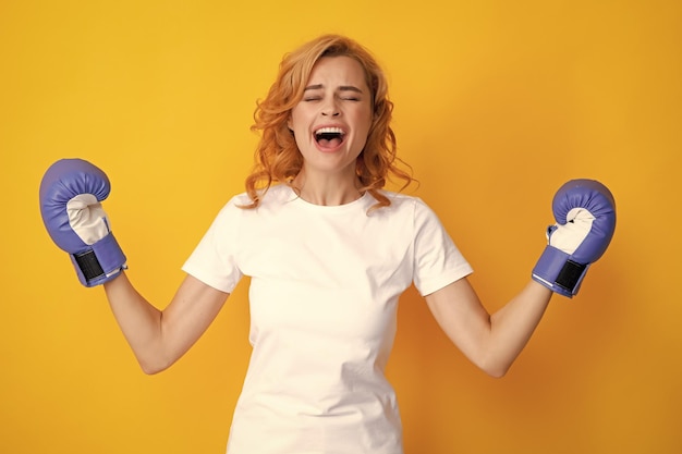 Winner female boxer with her hands raised excited Isolated on yellow background Excited woman