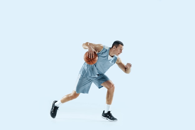 Winner. Young caucasian basketball player of team in action, motion in jump isolated on blue background. Concept of sport, movement, energy and dynamic, healthy lifestyle. Training, practicing.