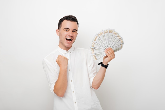 Winner young man holding a bunch of dollars on white background.