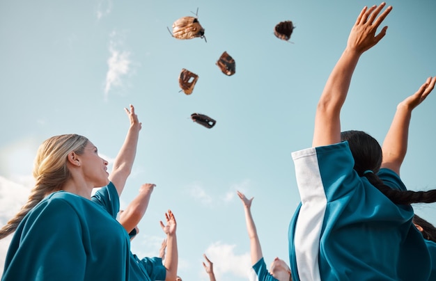 Winning team sports celebration and baseball women group throwing gloves in air for goal victory and feeling happy after game or match Teamwork softball and success of girl players below blue sky