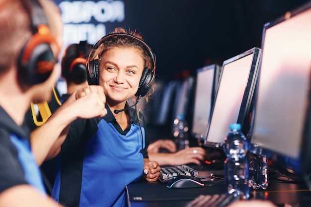 Winning. two young happy professional cyber sport gamers giving\
fist bump and celebrating success while participating in esports\
tournament. online video games