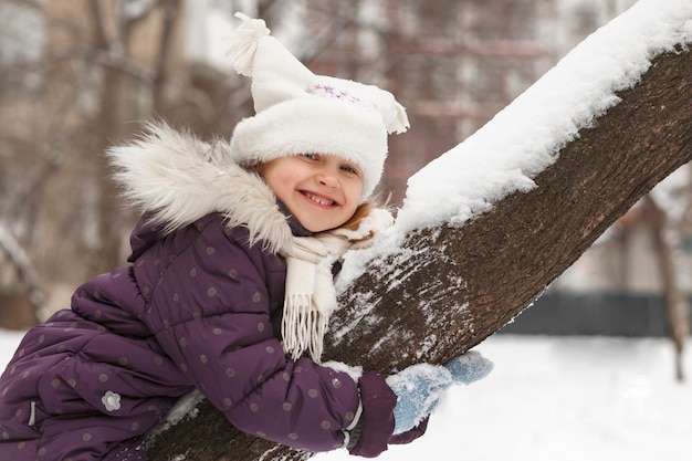 冬の活動の休日おかしい女の子は雪の木で幸せです冬のポジティブな肖像画の笑顔