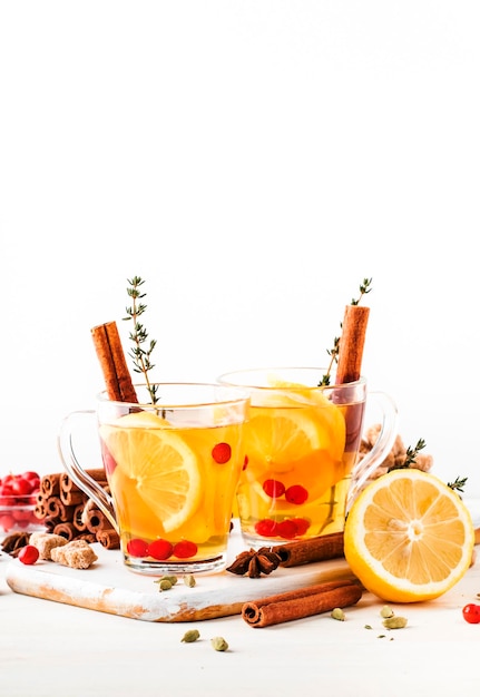 Winter or autumn healing hot tea with lemon cranberries thyme and spices white background copy space selective focus